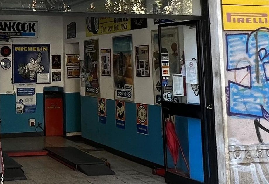 La parete interna dell'officina con i manifesti storici, l'omino Michelin, l'insegna Hankook e il cartello «Con voi dal 1922»